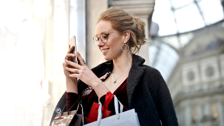 Woman with shopping bags looking at smartphone